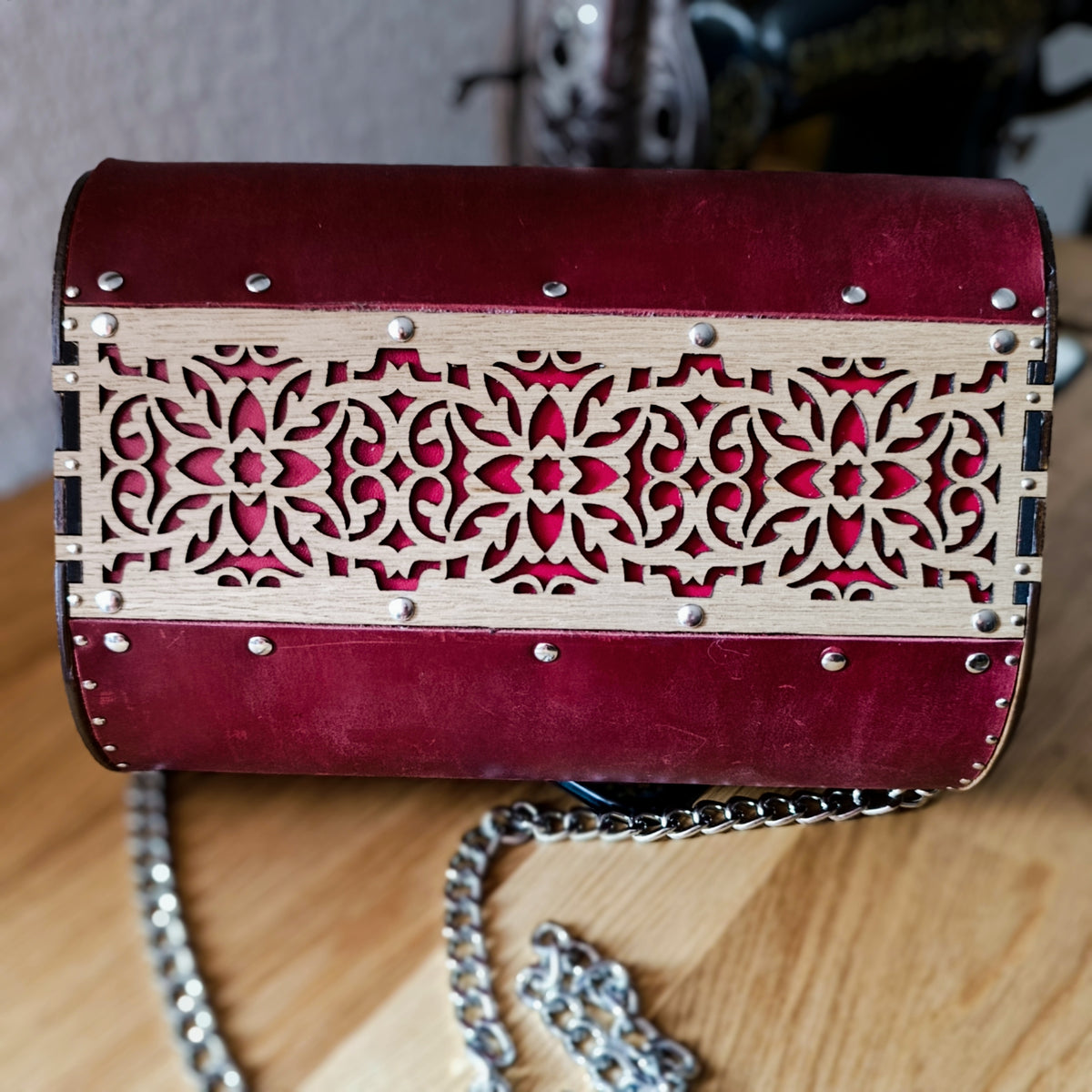 Pochette en cuir rouge foncé, bandeau central en bois ajouré gravé motif floral, vue de dos